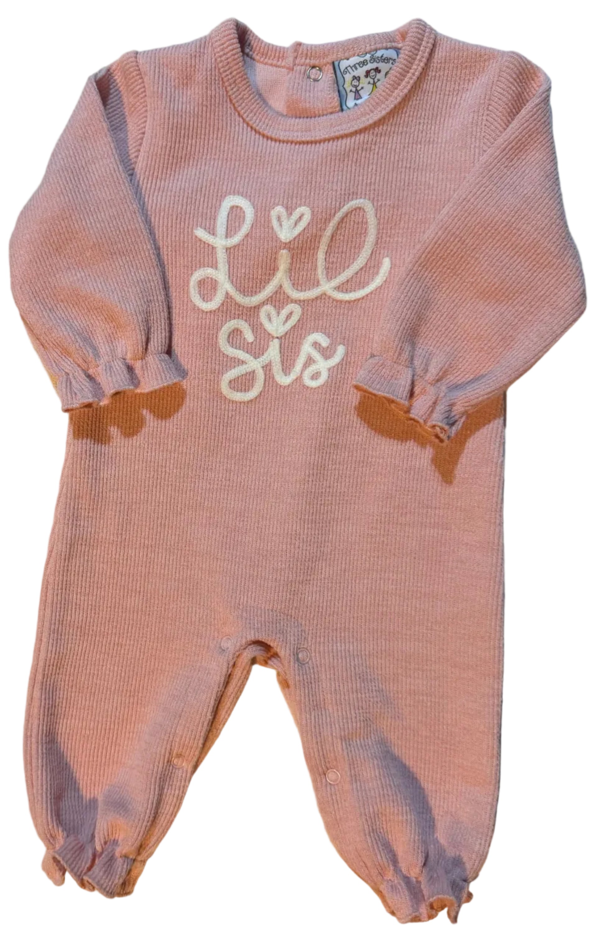 A pink knit baby romper with elastic leg cuffs and a white embroidered script on the front, laid flat on a white towel.