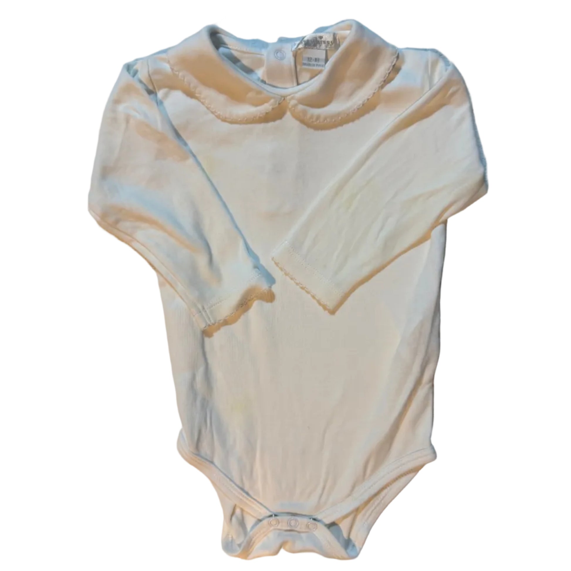 A light cream or off-white sleeveless baby bodysuit or romper laid flat on a textured white towel, with matching shorts folded on top.