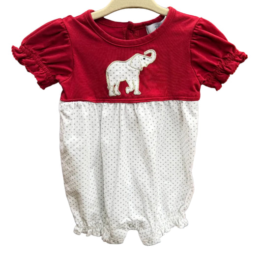 A toddler girl's short-sleeve romper hanging on a wooden hanger against a brick wall. The top half is a solid deep red with a white elephant applique, and the bottom half is white with tiny red polka dots.