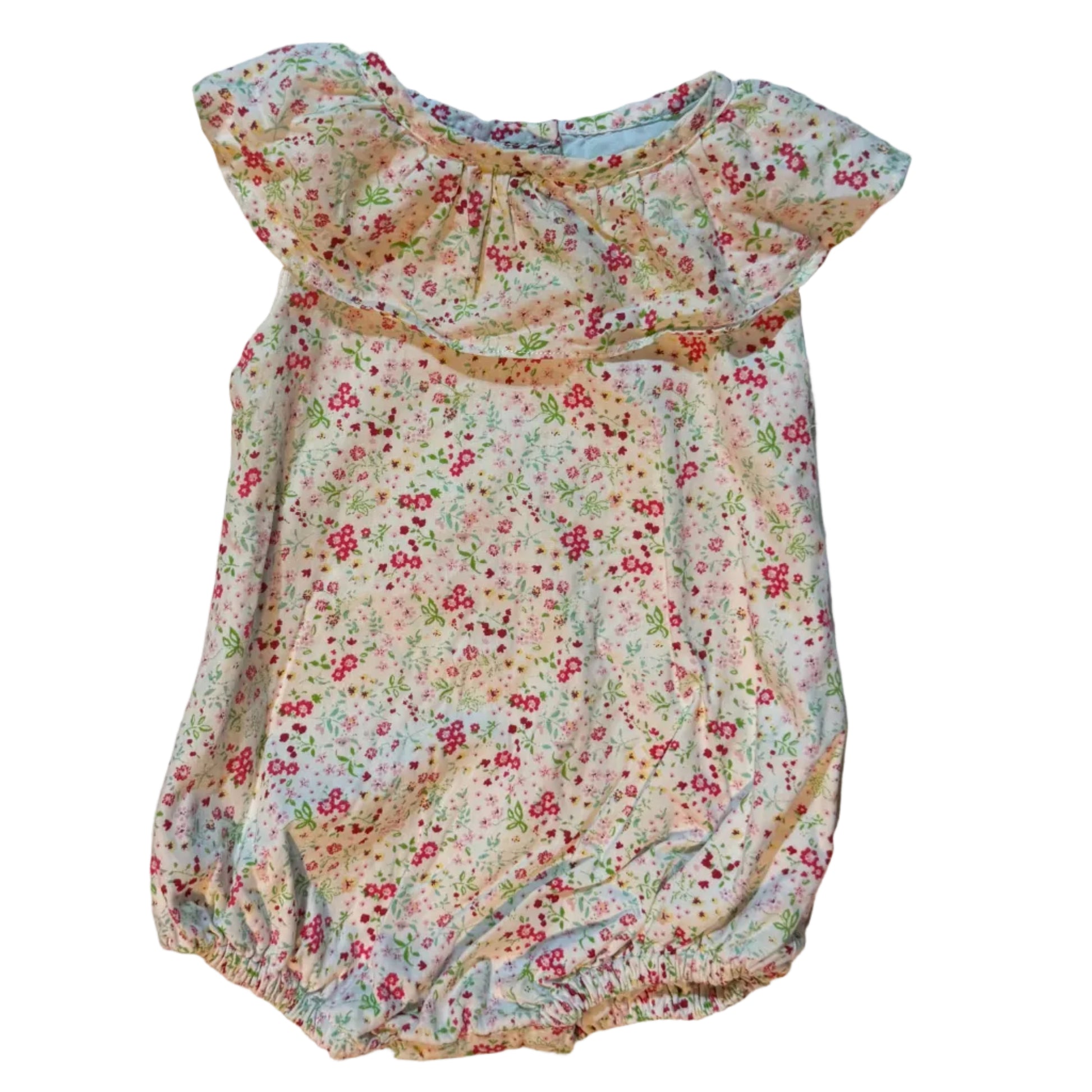 A baby romper with a small multicolor floral print on a cream base, laid flat on a white towel. The romper features a ruffled neckline and short sleeves.