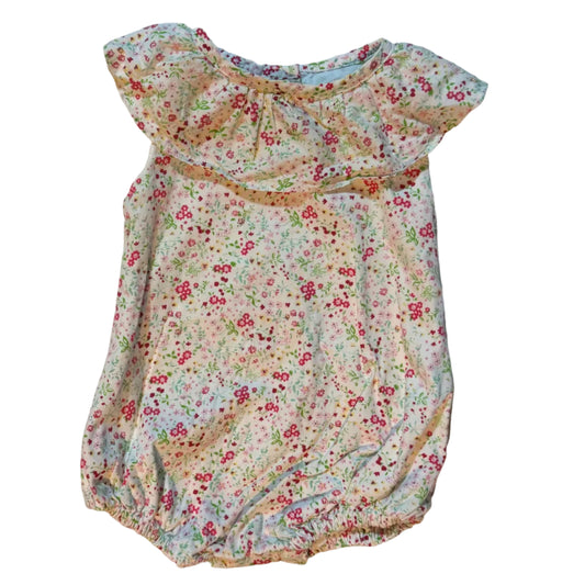 A baby romper with a small multicolor floral print on a cream base, laid flat on a white towel. The romper features a ruffled neckline and short sleeves.
