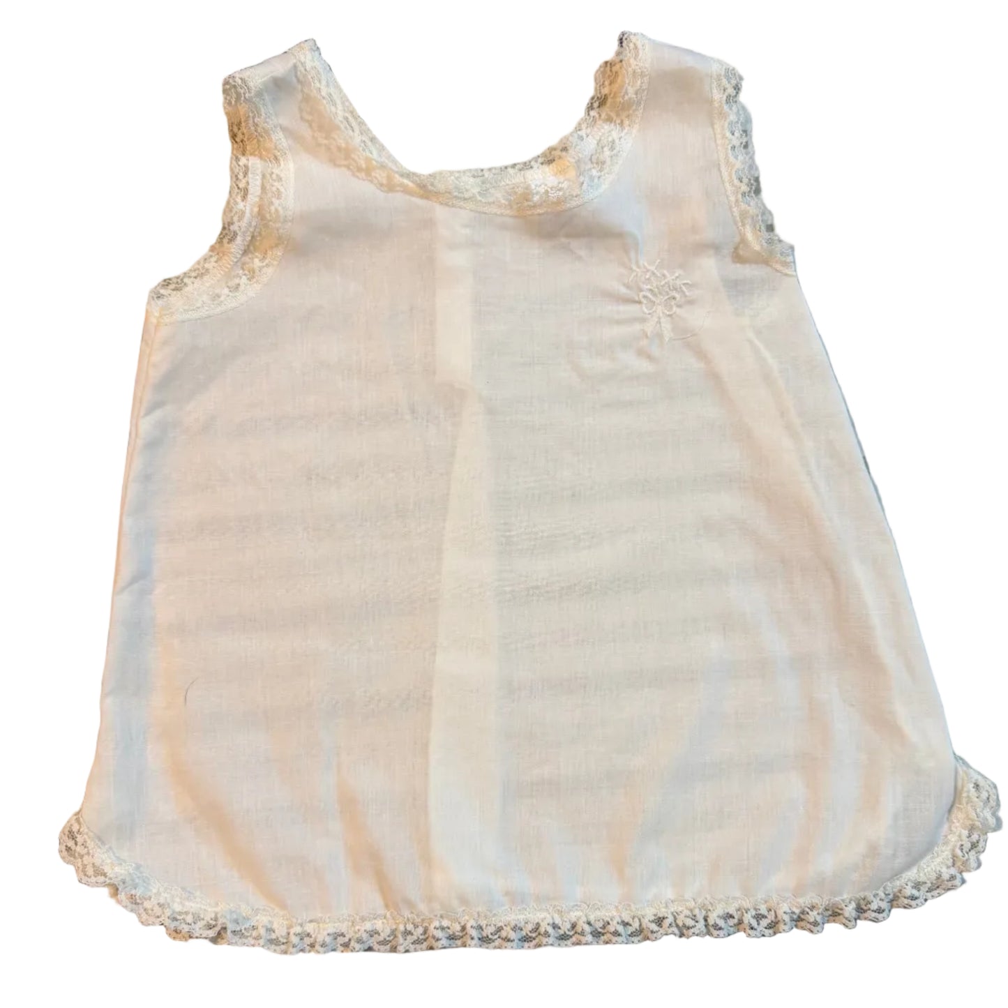 A cream-colored sleeveless baby top with delicate lace trim along the neckline and hem, laid flat on a striped blanket.