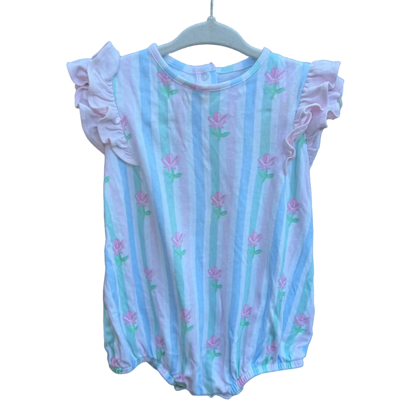 A baby girl's short-sleeve bubble bodysuit with ruffled sleeves, featuring vertical light blue and white stripes with pink flowers and green stems, hanging on a brick wall.