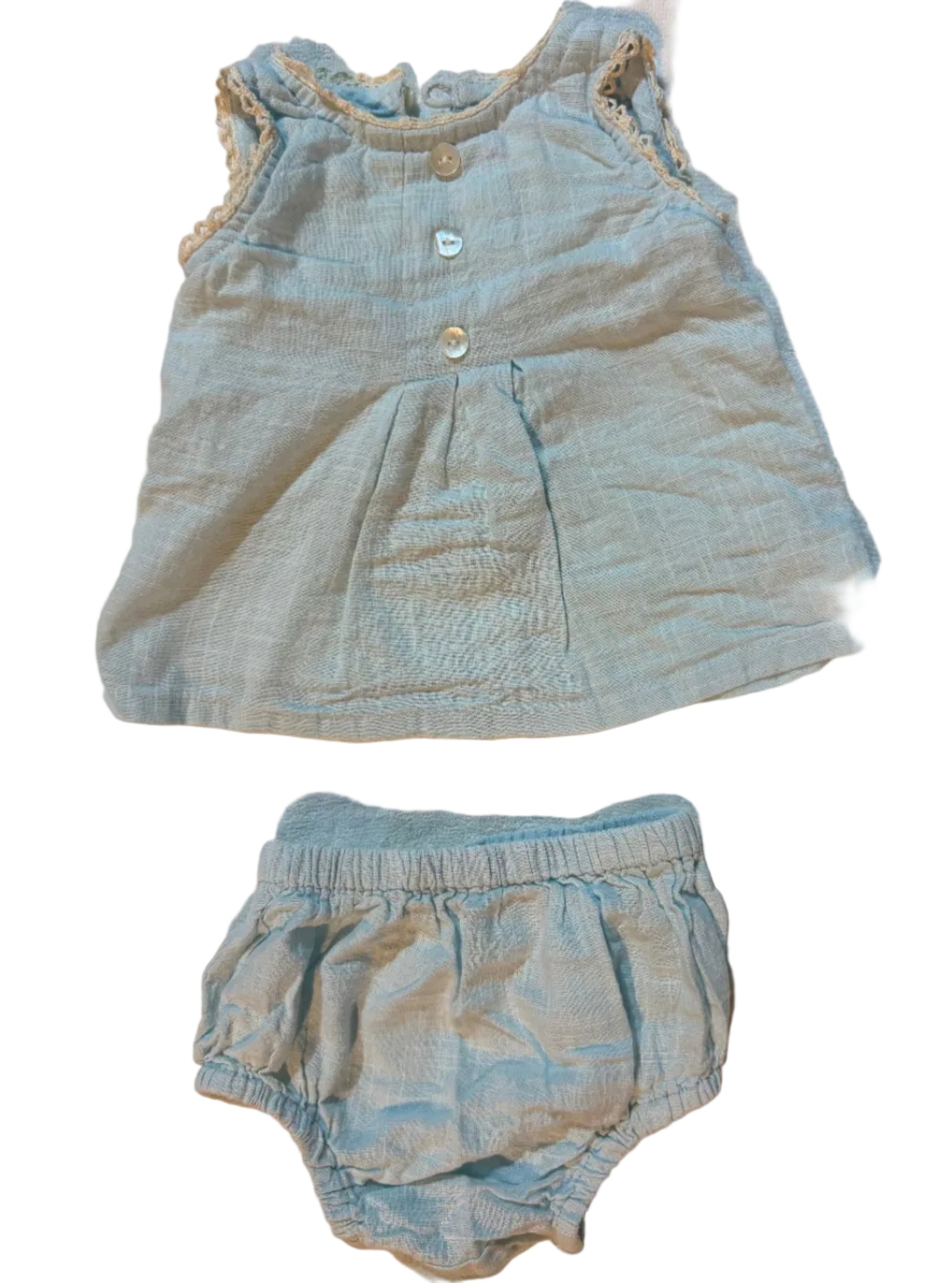 A two-piece baby clothing set consisting of a sleeveless top and matching high-waisted bottoms in a light blue-gray linen-like fabric, laid flat on a beige towel.