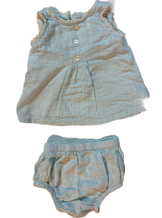 A two-piece baby clothing set consisting of a sleeveless top and matching high-waisted bottoms in a light blue-gray linen-like fabric, laid flat on a beige towel.
