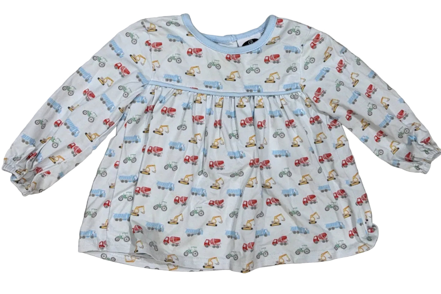 A toddler's long-sleeve dress with an all-over small vehicle print, laid flat on a light-colored wooden floor.