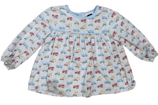 A toddler's long-sleeve dress with an all-over small vehicle print, laid flat on a light-colored wooden floor.