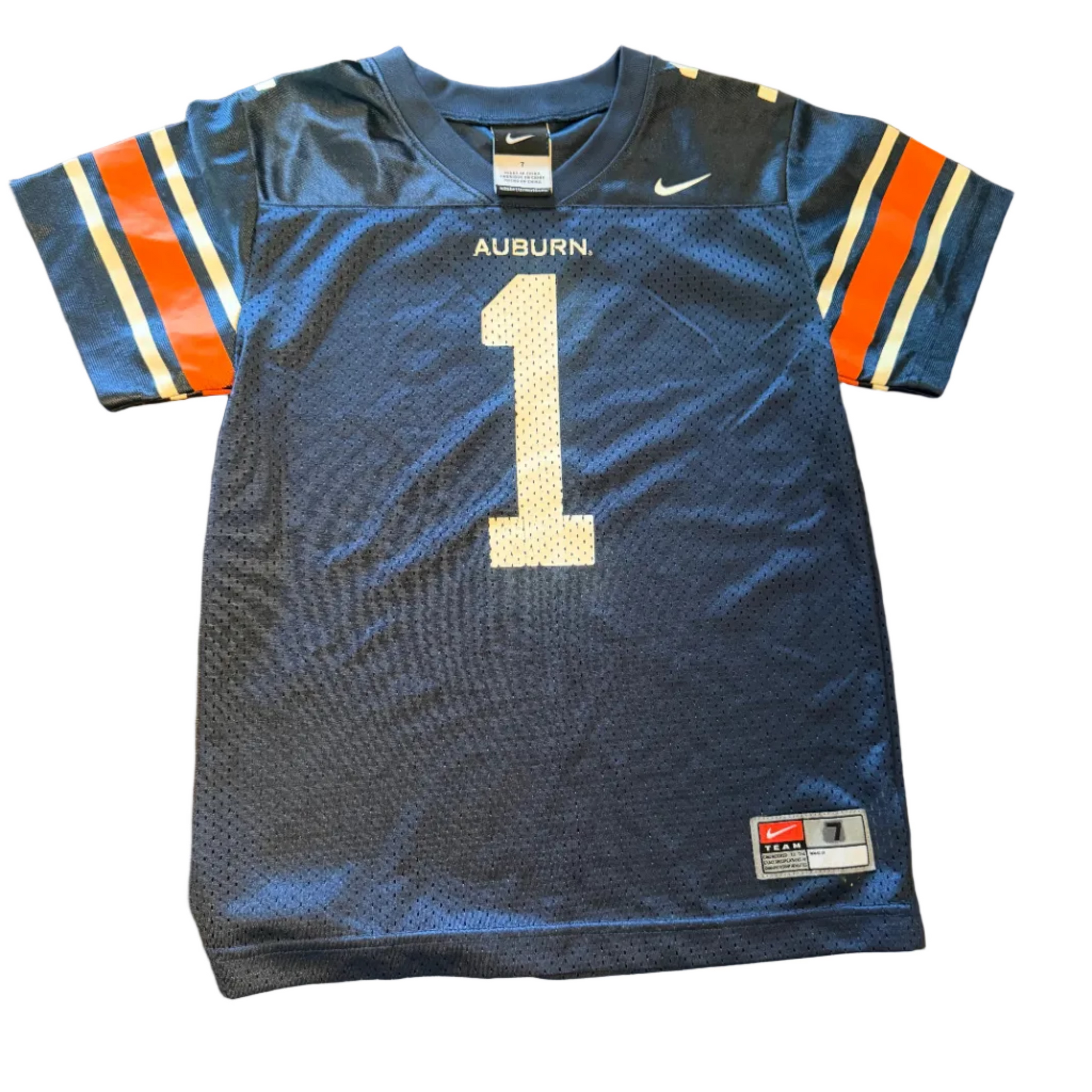 A navy blue Auburn Tigers football jersey with the number 1 on the front, laid flat on a wooden table. The jersey features orange and white sleeve stripes, 'AUBURN' and a white Nike swoosh on the chest, and a JHJ tag on the bottom right.